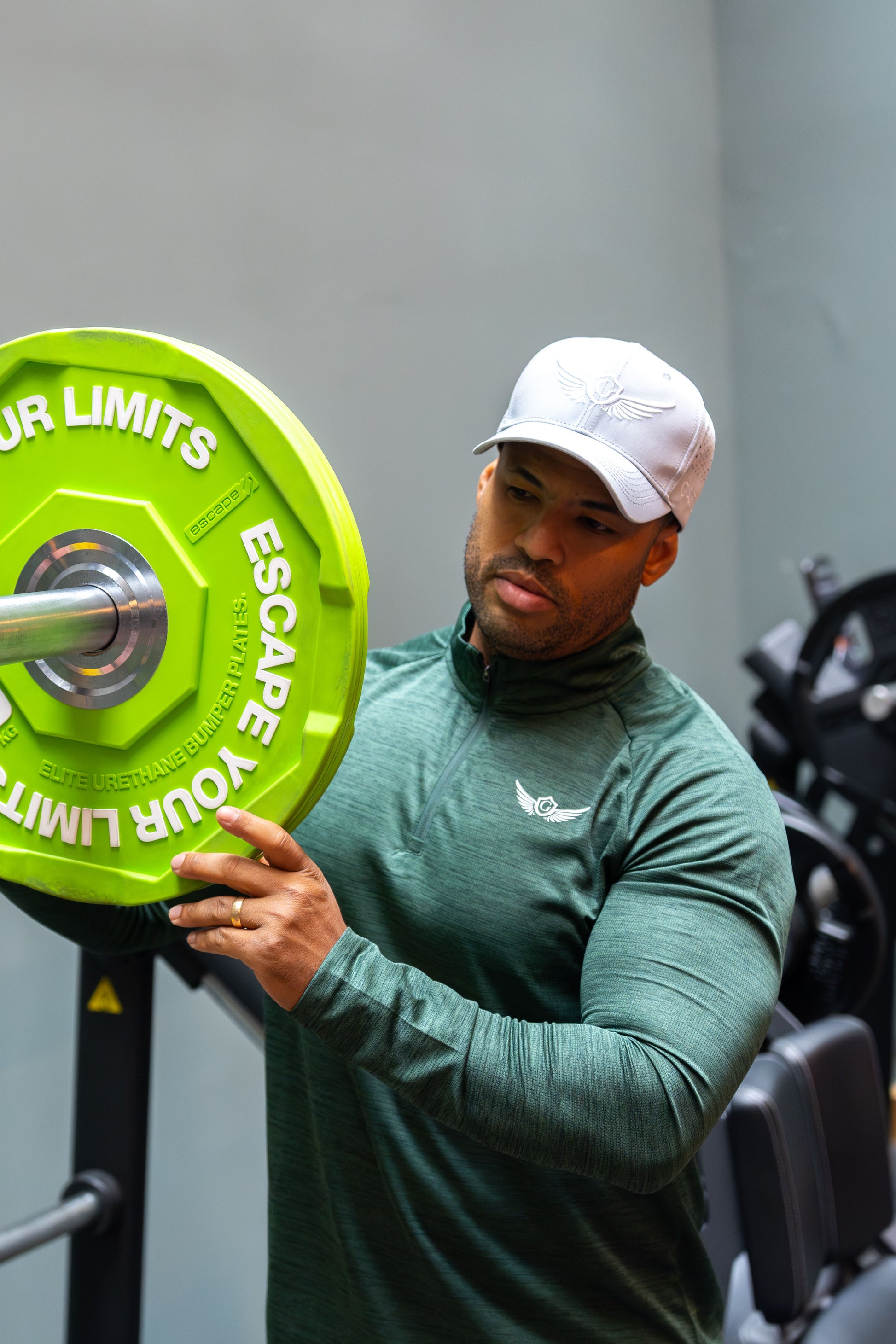 Person holding a green weight plate with motivational text in a gym setting