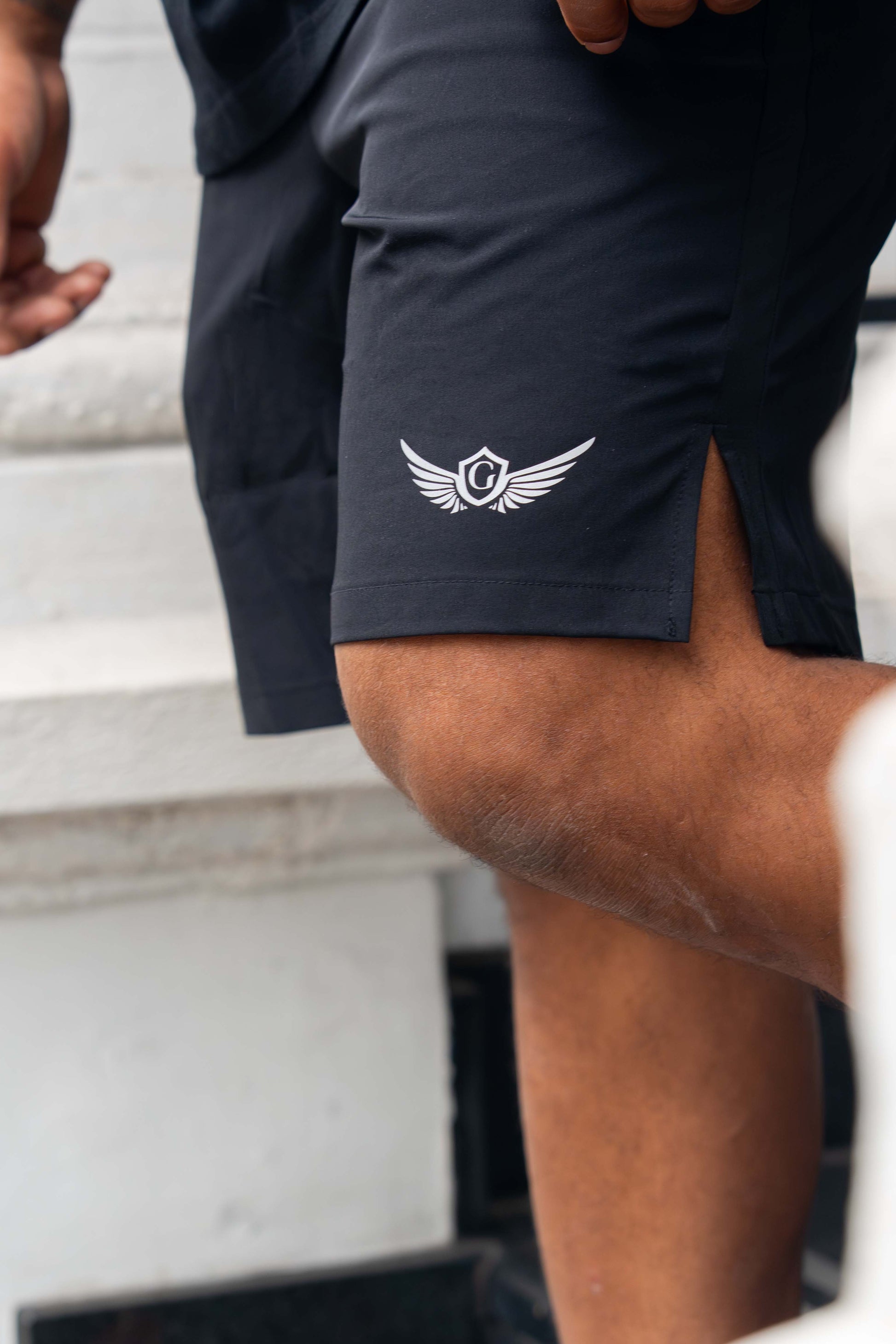 Person wearing black shorts with a logo on a blurred background