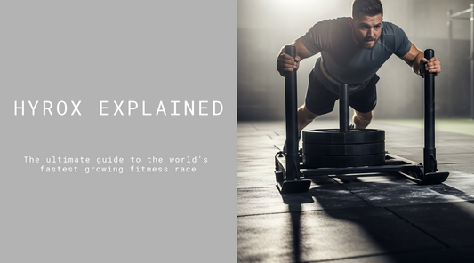 A man pushing a sled in a gym as part of the HYROX fitness challenge explained in the ultimate guide.